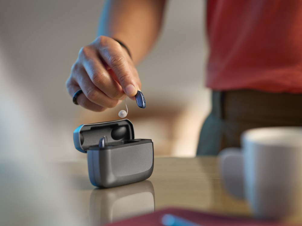 Rechargeable hearing aid being placed into its charging case, a device type serviced at Anne Arundel Audiology in Glen Burnie, MD